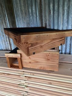 a wooden bench sitting on top of a pile of wood next to a metal wall