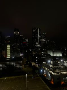 the city skyline is lit up at night with bright lights in the foreground and dark skies above