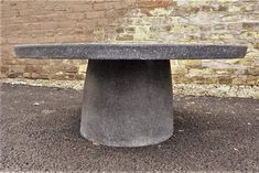 a concrete bench sitting in front of a brick wall