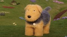 a stuffed dog sitting in the grass with flowers around it's neck and back