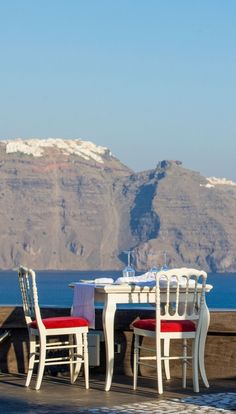 an outdoor dining area overlooking the ocean with mountains in the background