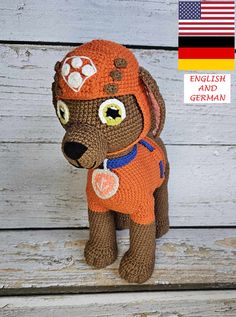 a stuffed dog wearing an orange shirt and hat with the german flag in the background