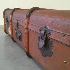 an old trunk is sitting on the floor next to another piece of luggage that has rusted metal latches and rivets