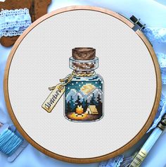 a cross stitch pattern with a mason jar and campfire in it on a white background