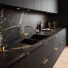 a kitchen with marble counter tops and gold faucets on the sink, along with black cabinets