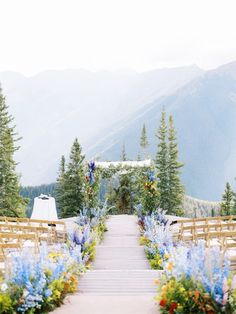 an outdoor ceremony setup with wooden chairs and flowers on the aisle leading up to the altar