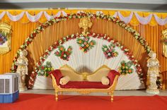 a stage set up for a wedding ceremony with red carpet and gold drapes on the wall