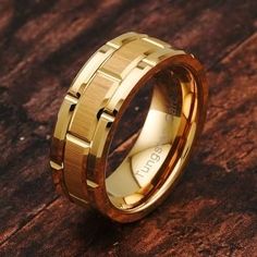 a gold wedding ring on top of a wooden table with the word love written in it