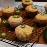 several muffins on a cooling rack with green peppers next to them and a cucumber