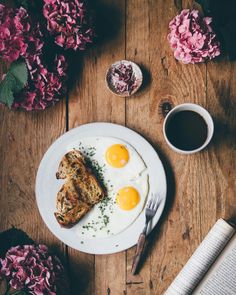 two fried eggs are on a plate next to a cup of coffee and a book