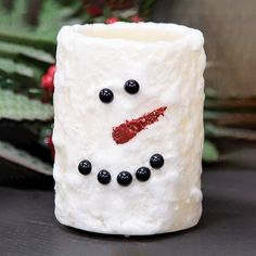 a white frosty cup with black beads and a snowman's face on it