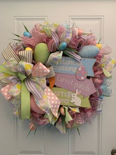 a pink and green mesh wreath with some baby's name tags on the front door