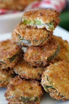 several fried food items stacked on top of each other in a white plate with another dish behind it