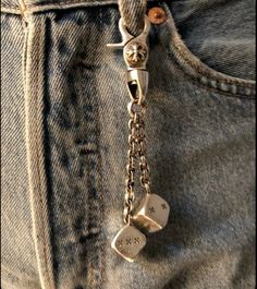 a pair of dice charms hanging from the back pocket of someone's jean pants