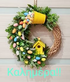 a wreath is hanging on the wall with eggs in it and a yellow birdhouse