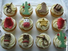 twelve cupcakes decorated with farm animals and cactuses are on a white tray