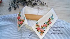 a white shirt with pink flowers on it and a wooden hanger next to it