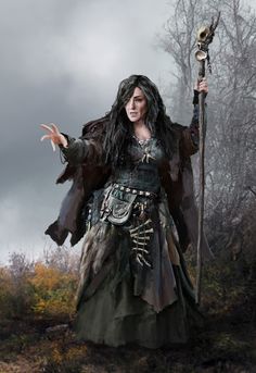 a woman dressed as a witch holding a staff