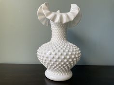 a white vase sitting on top of a wooden table