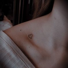 a woman with a small heart tattoo on her chest