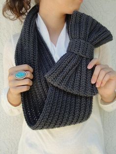 a woman wearing a gray knitted scarf with a turquoise stone ring on her finger