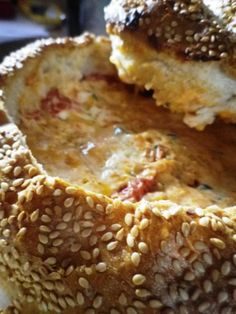 two sesame seed bagels stacked on top of each other with meat and cheese in the middle