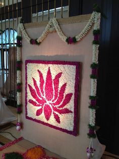 a large flowered wall hanging on the side of a building with flowers around it