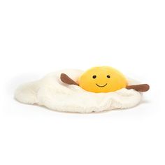 a stuffed animal that is laying on top of a white blanket with an egg in it's shell