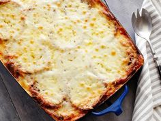 a square casserole dish with cheese on top and a fork next to it