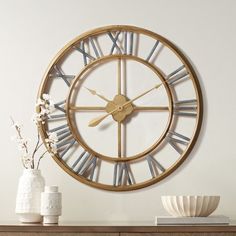 a large clock on the wall next to a vase with flowers