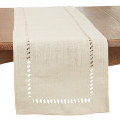 the table runner is made from natural linen and has white dots on it, along with an embroidered border