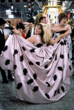 two women dressed in pink and black polka dots are dancing with each other at a party