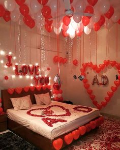 a bedroom decorated for valentine's day with red and white balloons