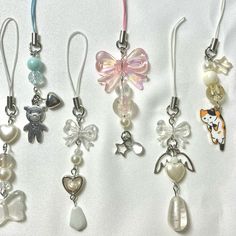 several charms are displayed on a white surface, including one with a bow and the other with an angel