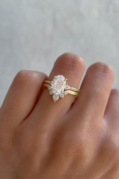 a woman's hand wearing a gold ring with an oval diamond in the middle