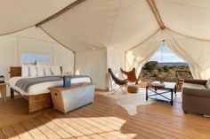 the inside of a large tent with wooden floors and white walls, overlooking an open field