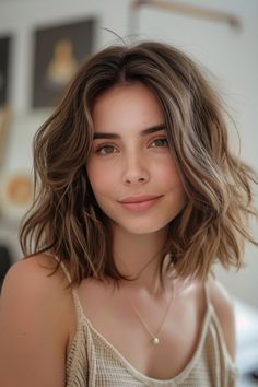 Young woman with wavy brown hair smiles gently, wearing a beige top. Hair For Cool Skin Tone, Macchiato Balayage, Brown Hair For Cool Skin Tone, Autumn Balayage, Copper Highlights On Brown Hair, Latest Hair Color Trends, Brown Hair Ideas, Neutral Skin, Light Brown Balayage