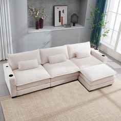 a living room with a large white couch and rugs on the floor in front of a window