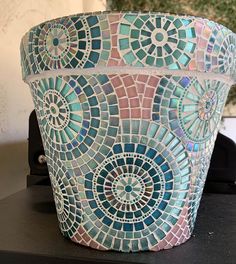 a pot sitting on top of a table covered in blue and pink mosaic tiles,