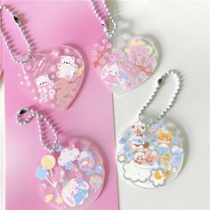 three heart shaped key chains on a pink and white background with teddy bears in the sky