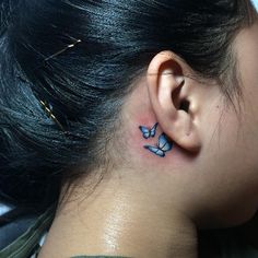 a woman with a butterfly tattoo on her left side behind the ear is looking down