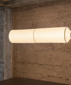 a white light hanging from the ceiling in a room with concrete walls and flooring