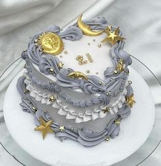 a three tiered cake decorated with gold stars and moon decorations on a glass plate