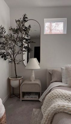 a bedroom with a tree in the corner and a mirror on the wall above it