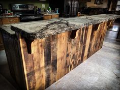 a kitchen island made out of wooden planks with granite counter tops and drawers on each side