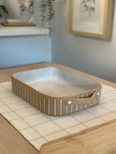 a white and brown tray sitting on top of a wooden table next to a potted plant