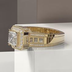 a gold ring with a white diamond in the center on top of a block wall