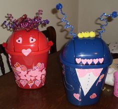 two plastic trash cans sitting on top of a wooden table next to each other with hearts painted on them