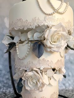 a wedding cake decorated with white flowers and pearls