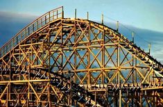 an amusement park roller coaster in the middle of the day with blue sky and clouds behind it